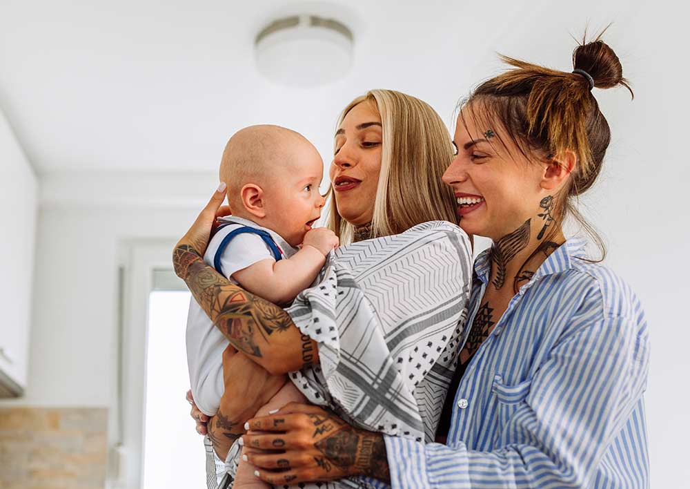 Couple in pajamas hugging a baby and smiling